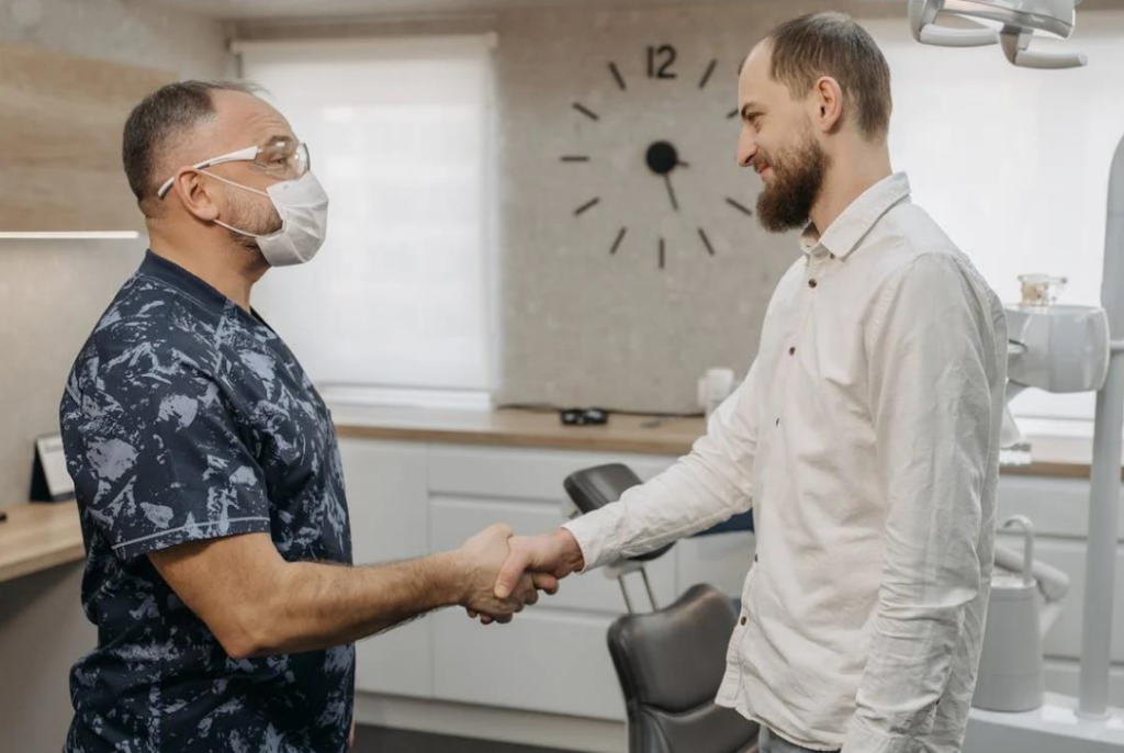 A dentist and patient shaking hands in the practice