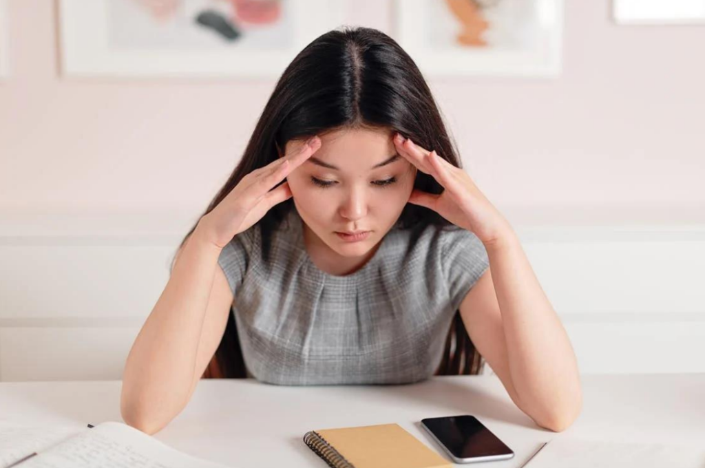 A receptionist with a stressed expression and head in hands