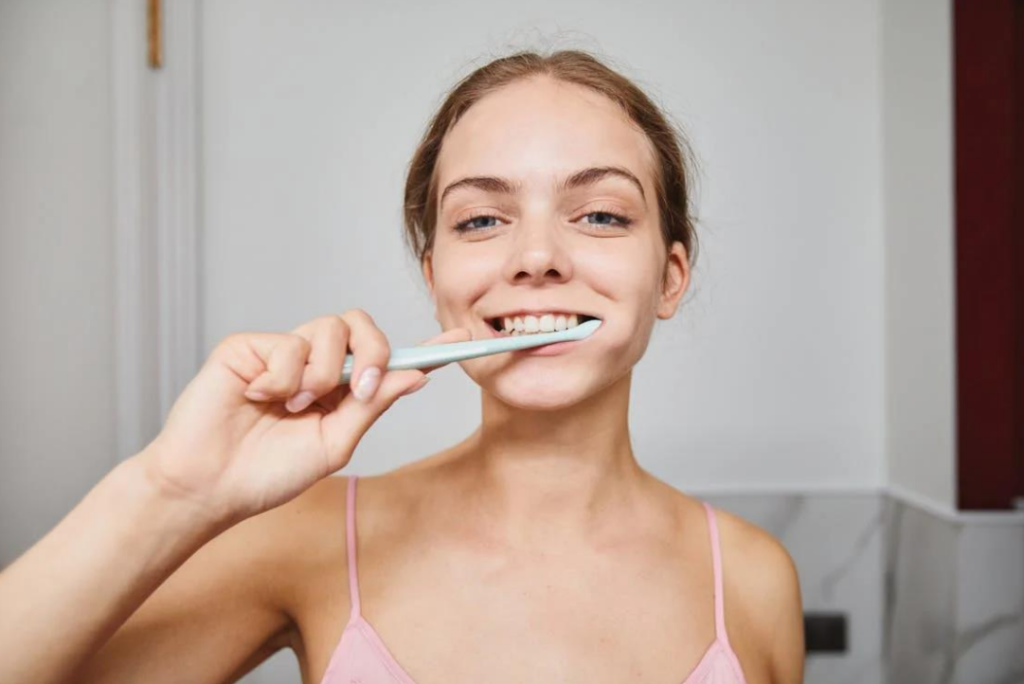 A smiling young woman brushing her teeth